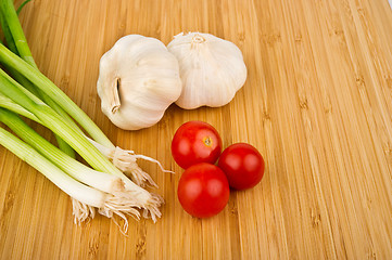 Image showing Green Onions, Tomatoes, and Garlic on Cutting Board