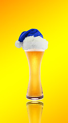 Image showing Beer and hat of Santa Claus on a yellow background