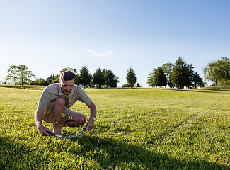 Image showing Senior man cutting grass with shears