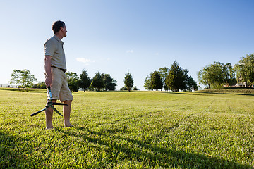 Image showing Senior man cutting grass with shears