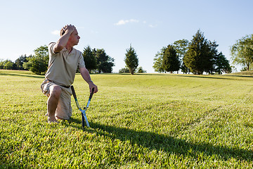 Image showing Senior man cutting grass with shears