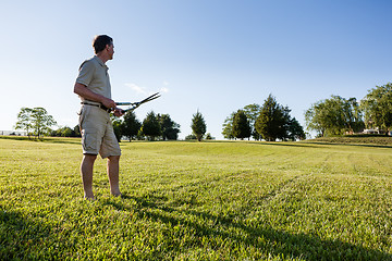 Image showing Senior man cutting grass with shears