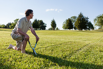 Image showing Senior man cutting grass with shears