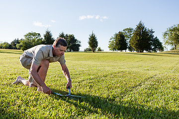 Image showing Senior man cutting grass with shears