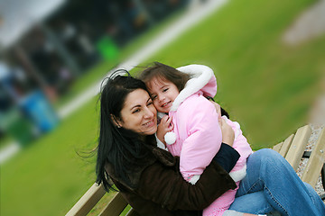 Image showing Diverse mom and daughter sitting in the bench