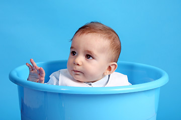 Image showing Portrait of a happy baby boy on blue bucket isolated on blue bac