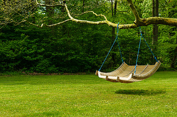 Image showing Swing bench in lush garden