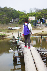 Image showing Asian woman walking along a wooden bridge