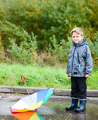 Image showing Boy with umbrella in puddle