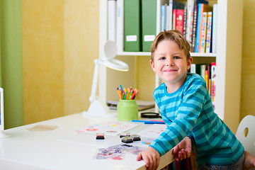 Image showing Happy school boy doing homework