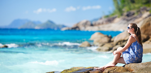 Image showing Young woman relaxing on rocky coast