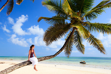 Image showing Young woman sitting on palm tree