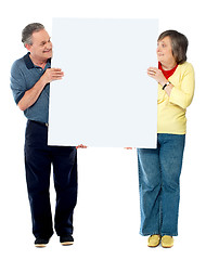 Image showing Mature couple presenting blank white billboard