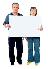 Image showing Happy senior couple holding a white placard