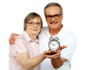 Image showing Aged couple with alarm clock on plam