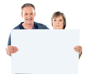Image showing Smiling aged couple displaying blank banner