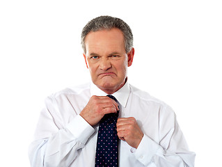 Image showing Serious businessman adjusting his tie