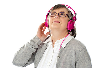 Image showing Old woman looking up, lost in musical world