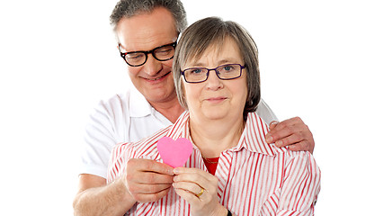 Image showing Old couple facing camera with focus on paper heart