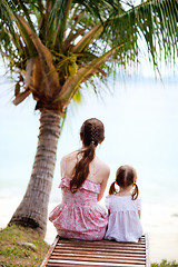 Image showing Mother and daughter sitting under palm