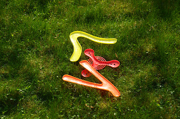 Image showing flying boomerang toys lying on grass. Outdoor game 