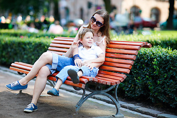 Image showing Mother and son sitting on bench in park