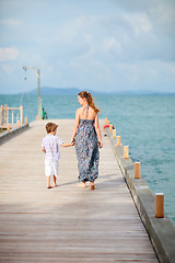 Image showing Mother and son walking along jetty