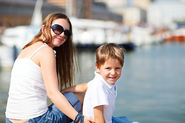 Image showing Mother and son sitting on jetty in city center