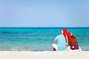 Image showing Romantic couple in Santa hats sitting on tropical beach