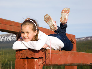 Image showing A girl lies on the balance beam and smiling