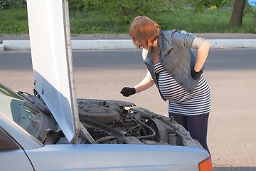 Image showing Pregnant Woman Trying to Repair the Car