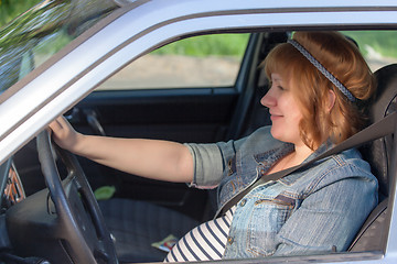 Image showing Pregnant woman fastening seat belt in the car