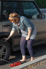 Image showing Pregnant woman pumping up the wheel