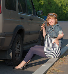 Image showing Pregnant Woman with a Wheel Brace near Car