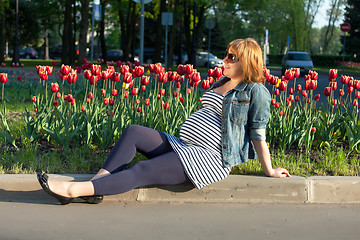 Image showing Pregnant woman sitting near tulip flowerbed