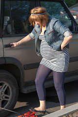 Image showing Pregnant woman pumping up the wheel