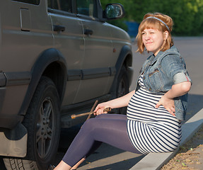 Image showing Pregnant Woman with a Wheel Brace near Car