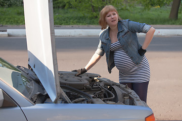 Image showing Pregnant Woman Trying to Repair the Car