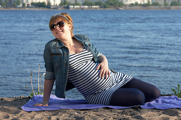 Image showing Pregnant woman sitting on the river coast
