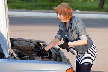 Image showing Pregnant Woman Trying to Repair the Car