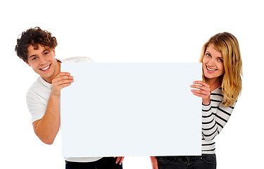 Image showing Attractive smiling couple holding a blank whiteboard