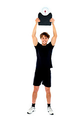 Image showing Male athlete holding weighing machine over his head