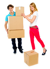 Image showing Young couple holding and moving boxes