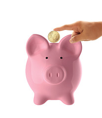 Image showing Hand putting coin into the pink piggy bank