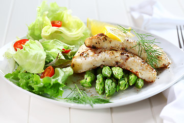 Image showing Fried fish on green asparagus with salad