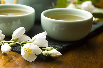 Image showing Green tea with jasmine in cup and teapot on wooden table