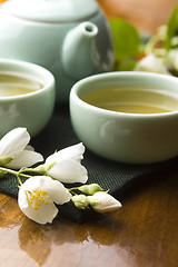 Image showing Green tea with jasmine in cup and teapot on wooden table