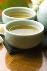 Image showing Green tea with jasmine in cup and teapot on wooden table