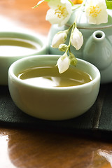 Image showing Green tea with jasmine in cup and teapot on wooden table