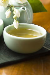 Image showing Green tea with jasmine in cup and teapot on wooden table